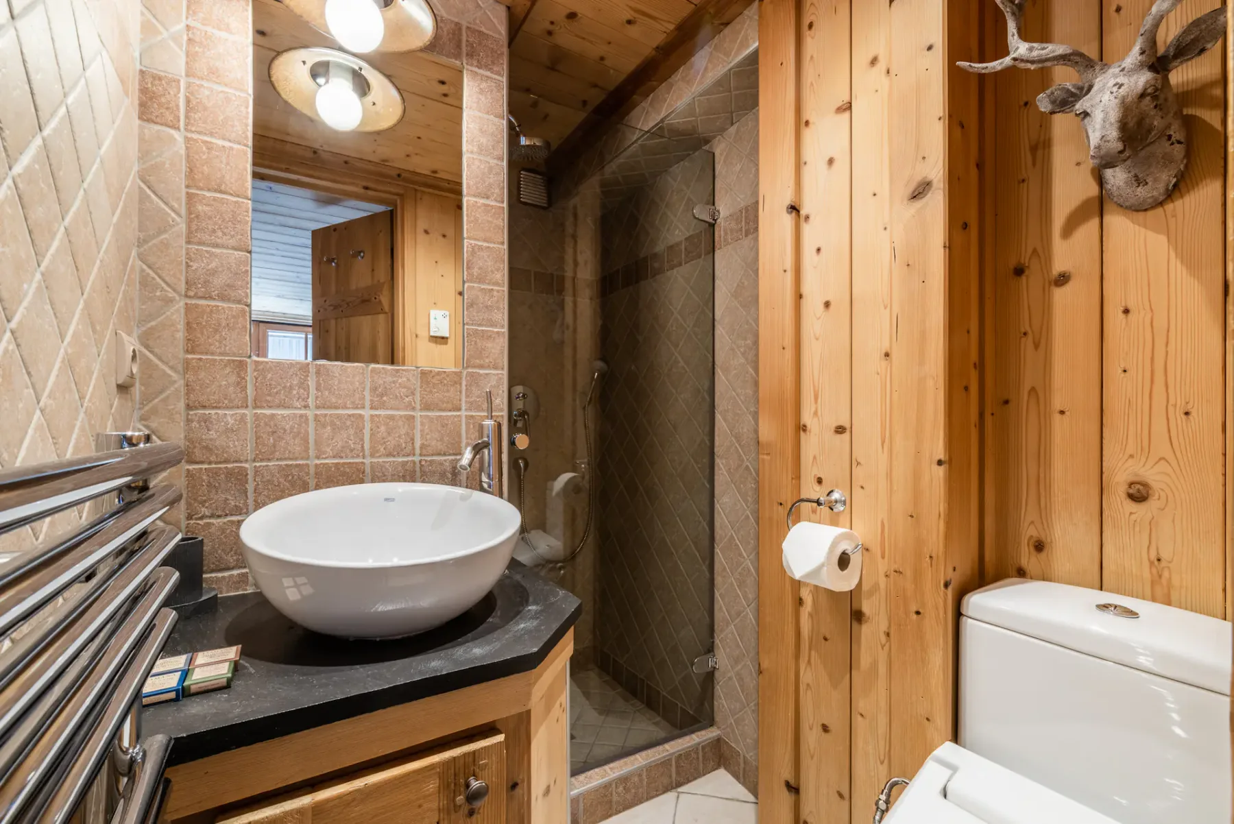 A bathroom with a vessel sink, tiled walls, and a glass shower.