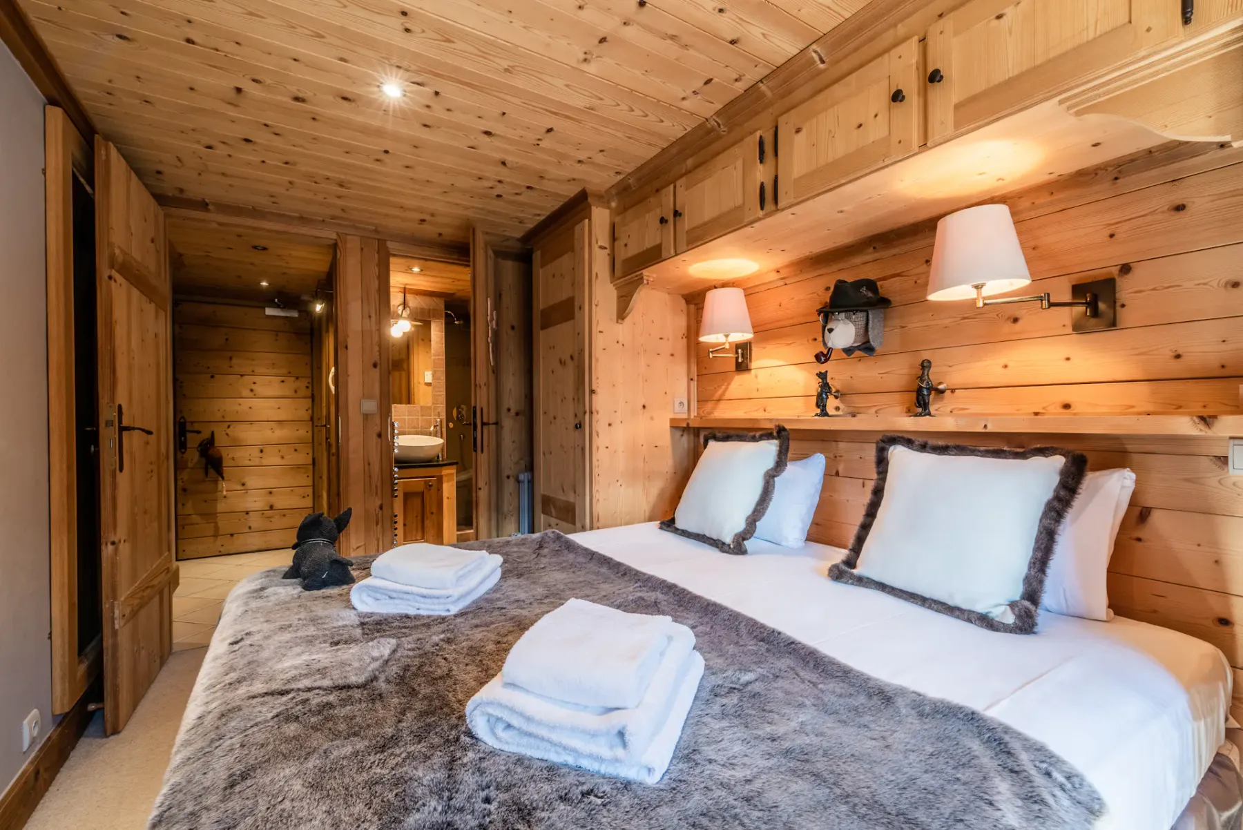 A wood-paneled bedroom with a double bed and folded towels.