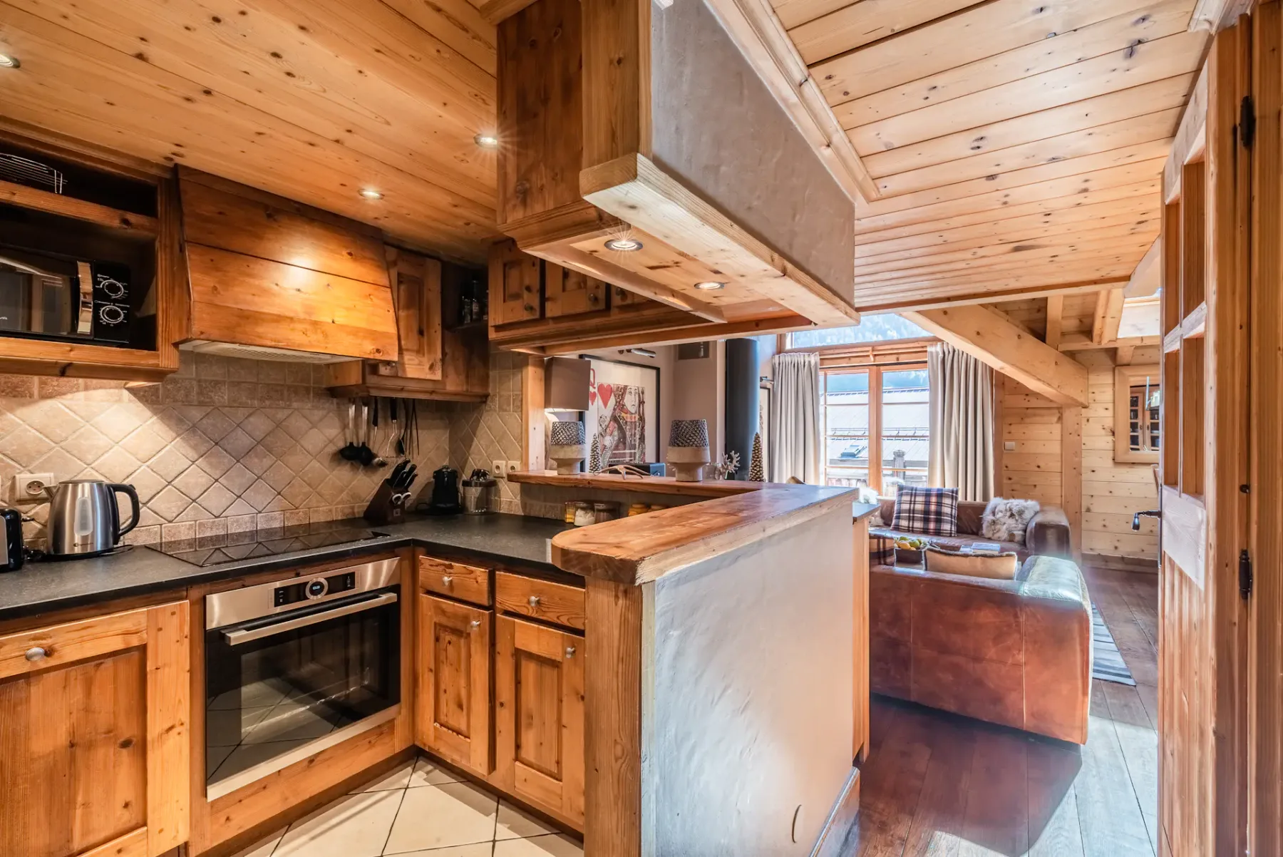 A wood-paneled kitchen opens onto a living area with seating.