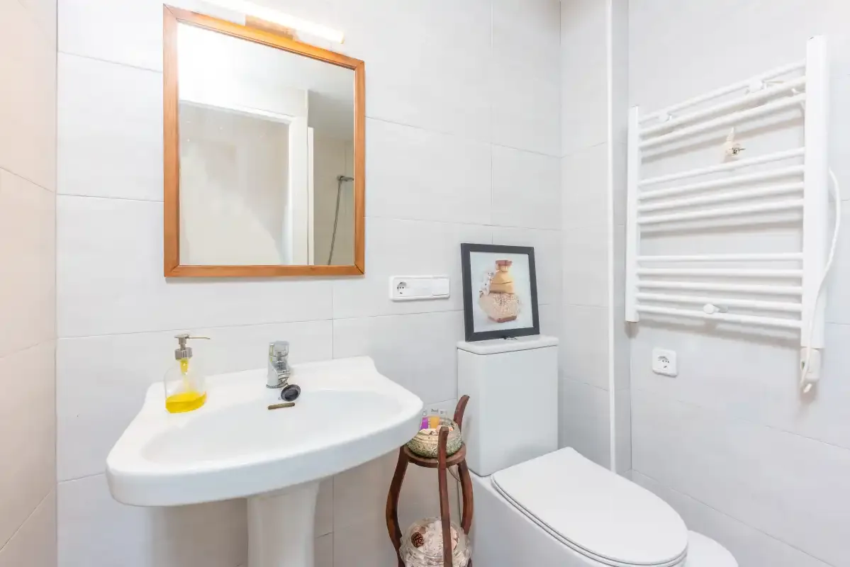 Un baño luminoso con lavabo, espejo e inodoro.