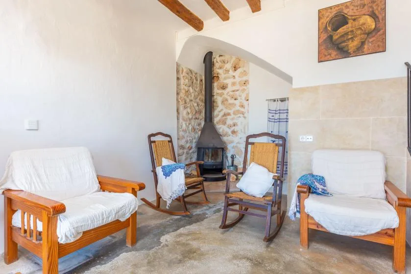 Una sala rústica con asientos de madera dispuestos alrededor de una chimenea.