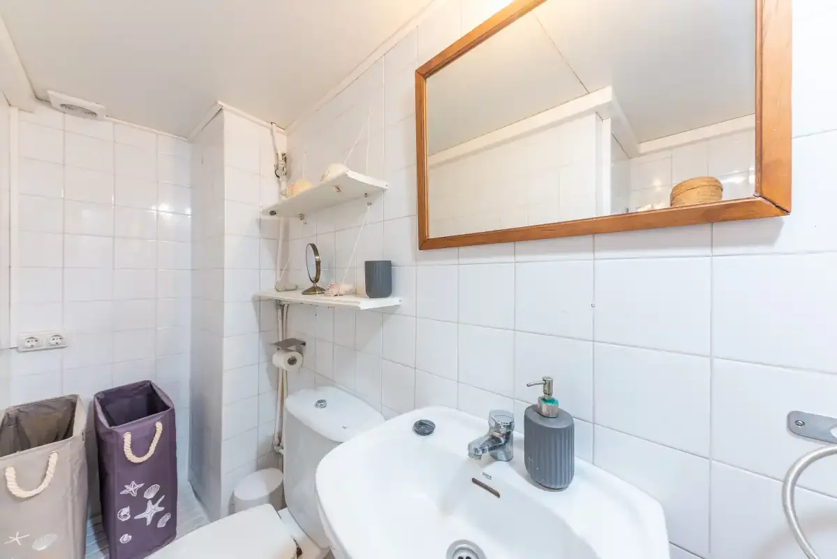Un baño alicatado con lavabo y un espejo grande en la pared.