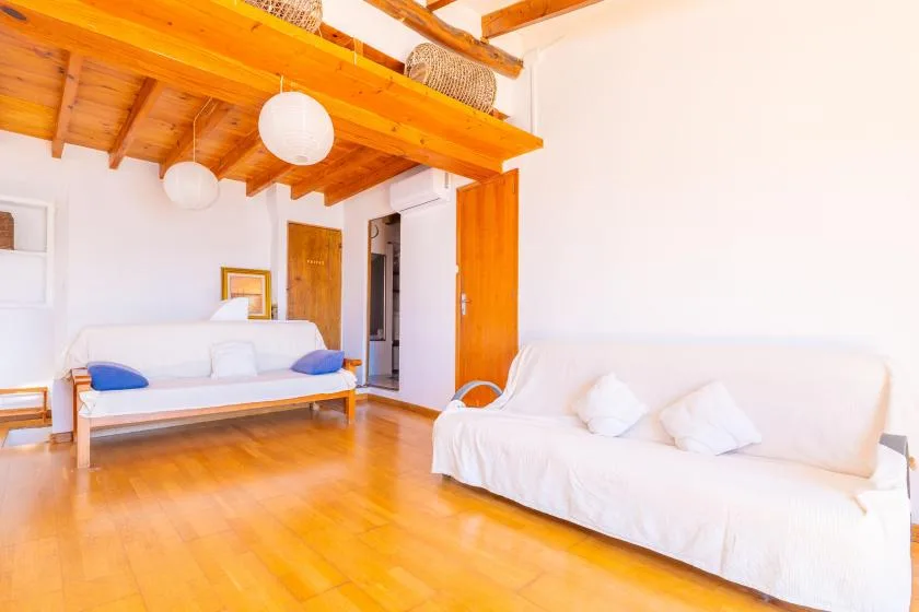 Una sala luminosa con asientos blancos, suelo de madera y vigas expuestas en el techo.