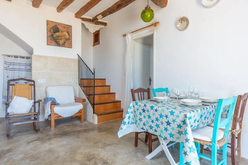 Un comedor con un mantel estampado y una escalera de madera junto a los asientos.
