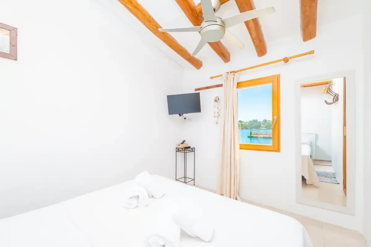 Un dormitorio luminoso con una cama, vigas vistas y una ventana con vistas al agua.