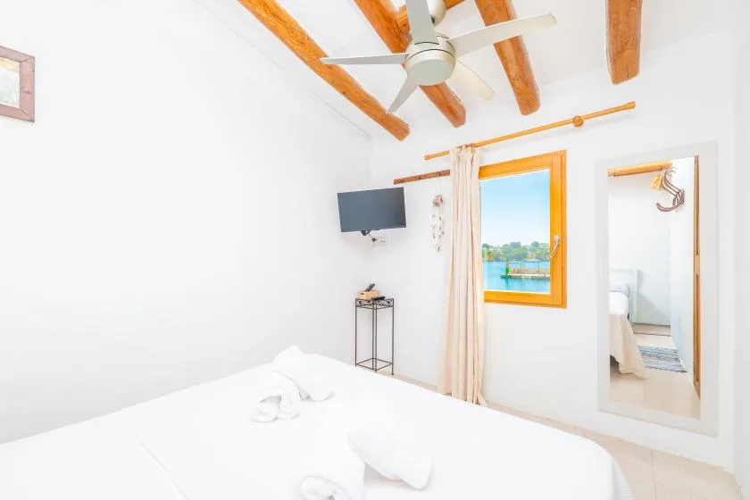 Un dormitorio luminoso con vigas de madera a la vista y una ventana con vistas al agua.