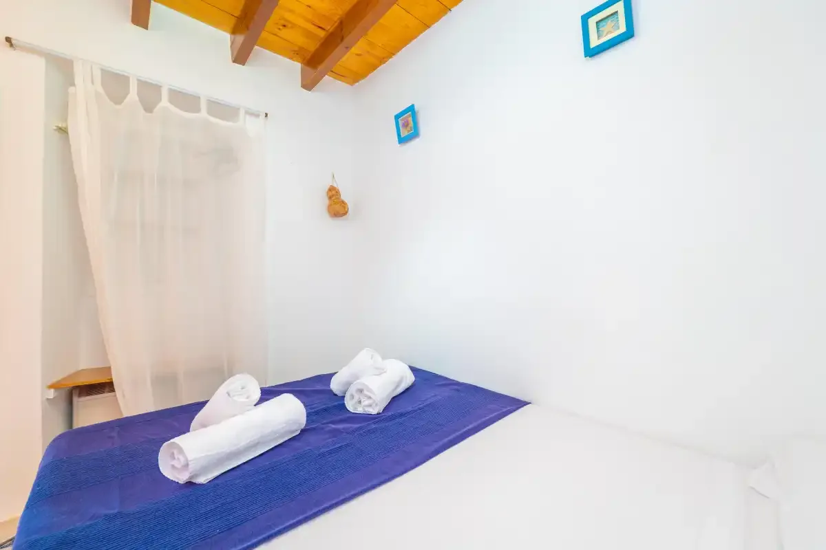 Dormitorio con una colcha azul y toallas dobladas.
