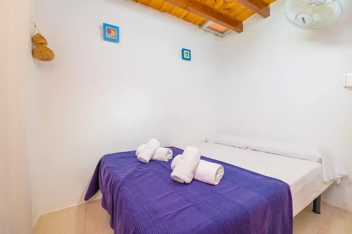 Un dormitorio con una cama cubierta con ropa de cama morada y toallas dobladas.