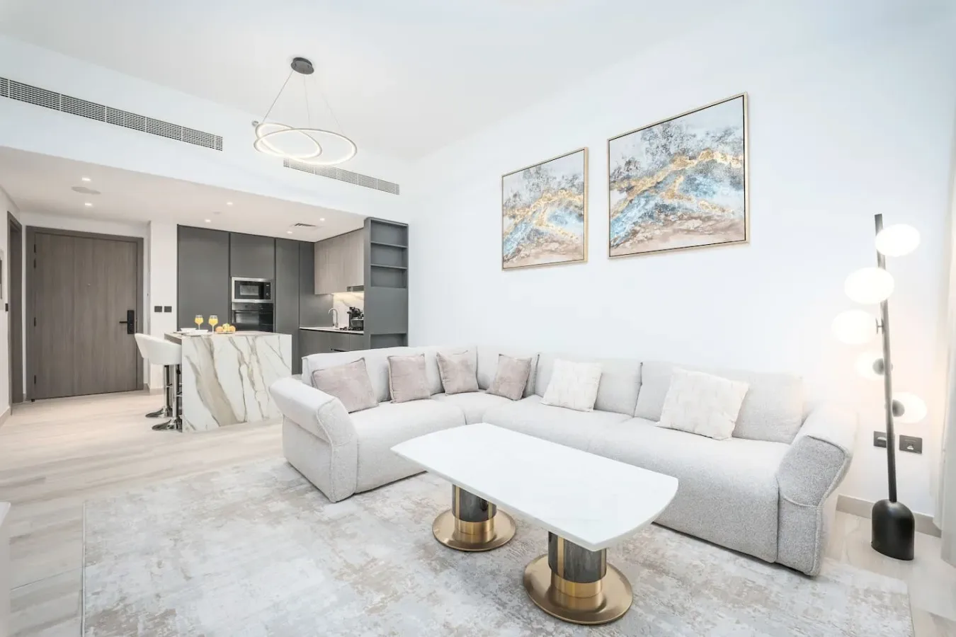 Una sala luminosa con sofá seccional, mesa de centro y cocina abierta.