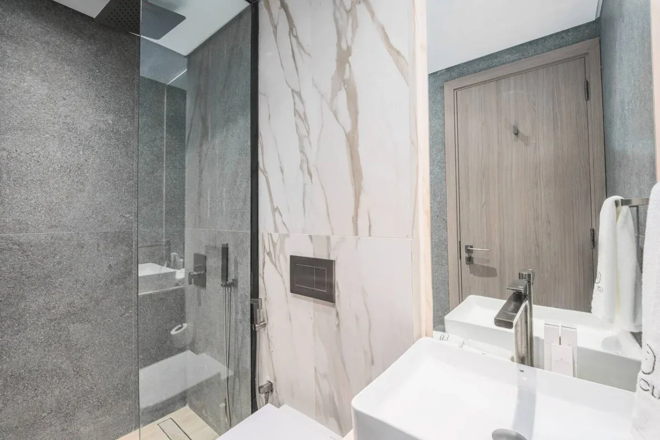 Un baño moderno con una ducha de vidrio y un lavabo blanco.
