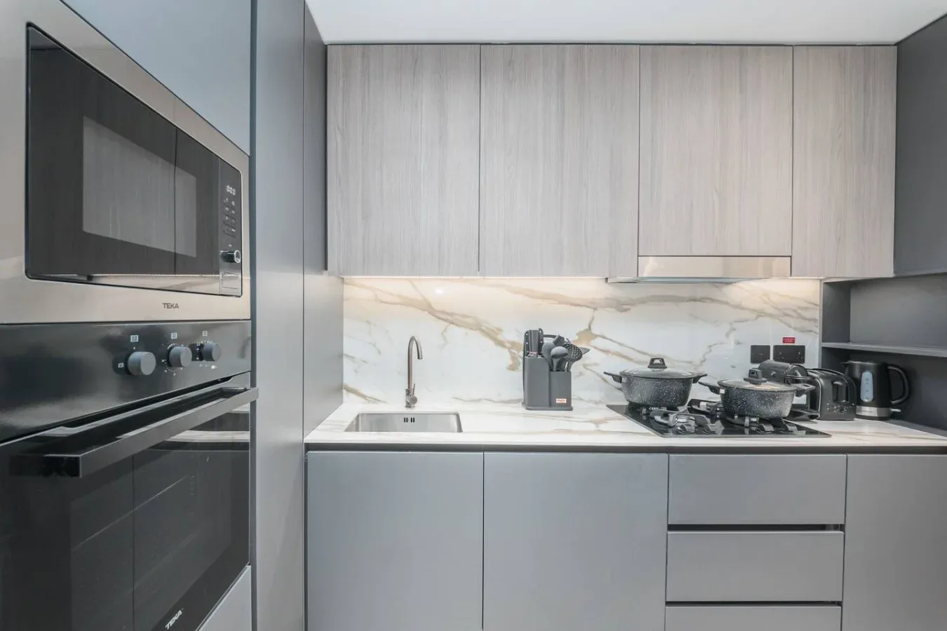 Una cocina moderna con electrodomésticos integrados, un fregadero y una placa de cocina.