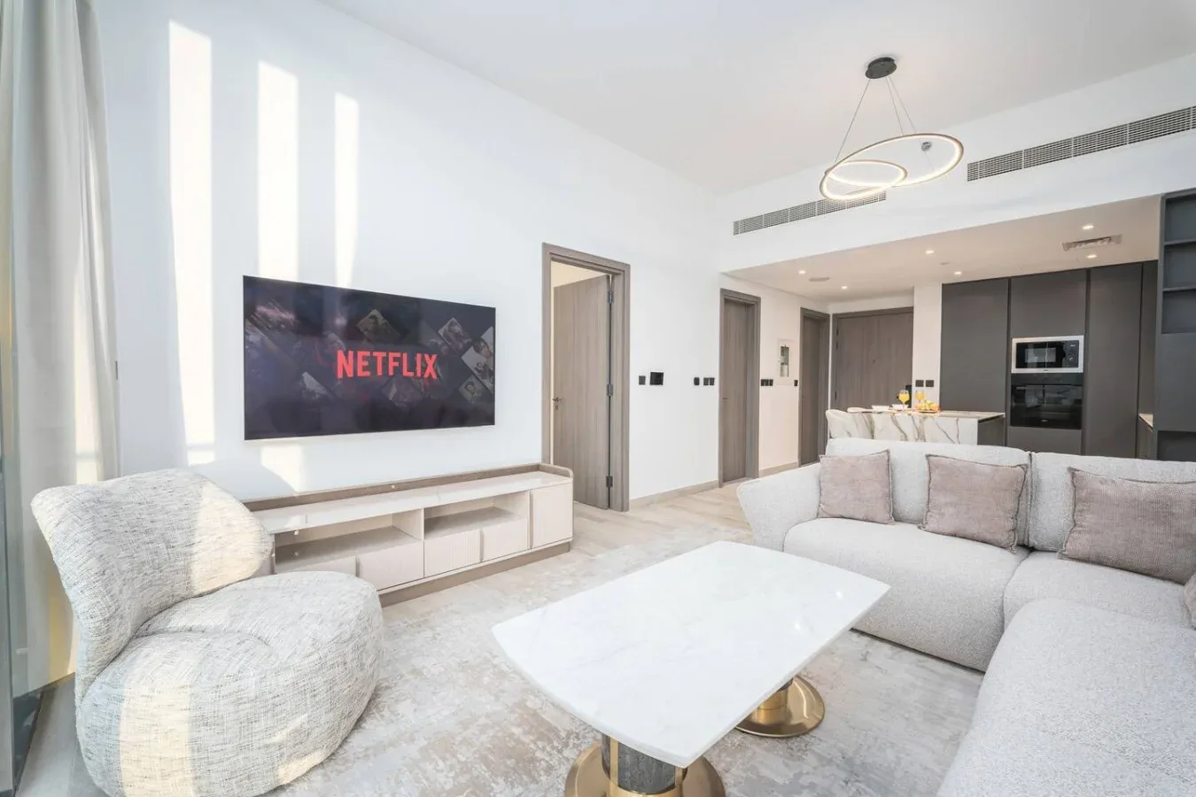 Una sala luminosa con asientos, una mesa de centro y un televisor en la pared.