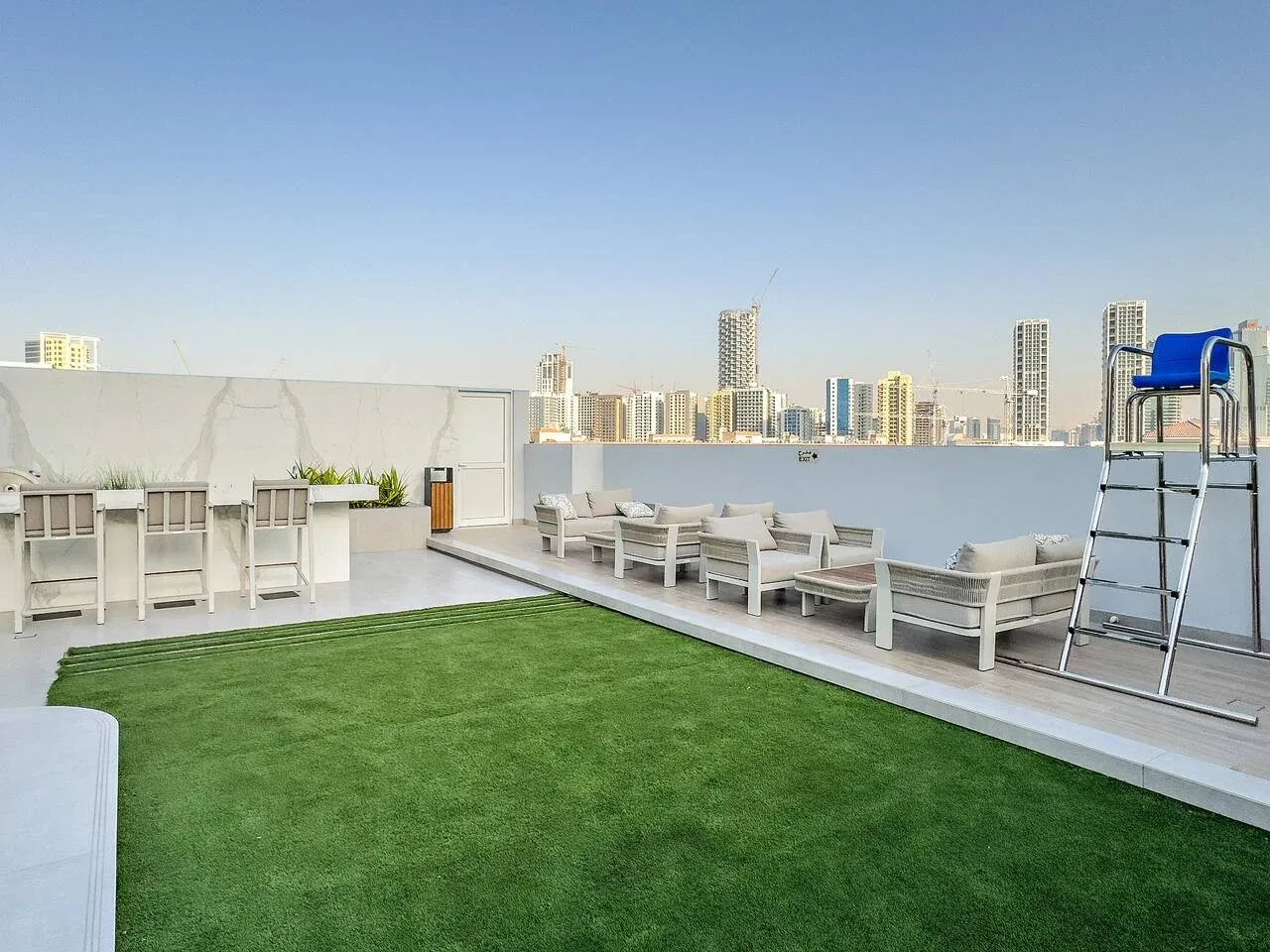 Una terraza en la azotea con asientos al aire libre, césped artificial y vistas a la ciudad.