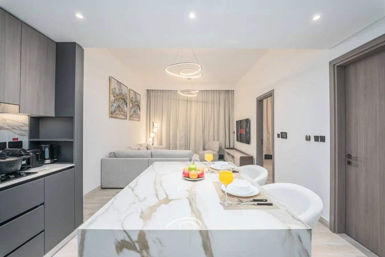 Una luminosa sala-comedor de planta abierta con cocina y una mesa de aspecto marmolado.