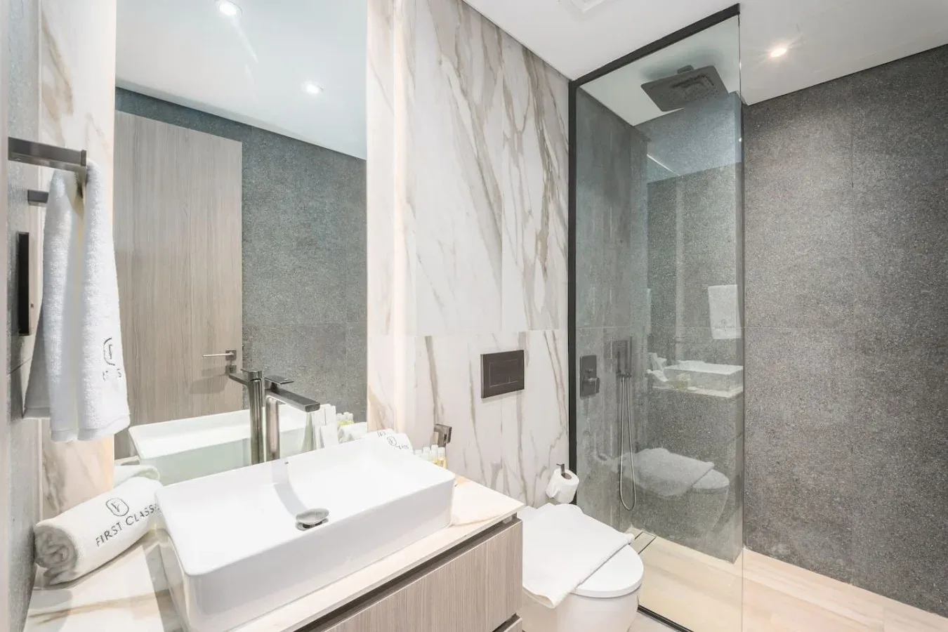Un baño luminoso con lavabo sobre encimera y ducha de vidrio.