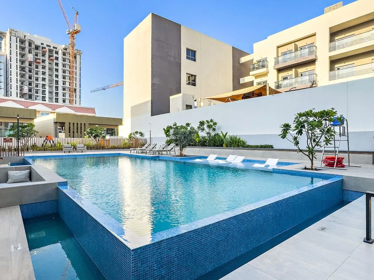Una piscina al aire libre está rodeada de asientos y edificios modernos.