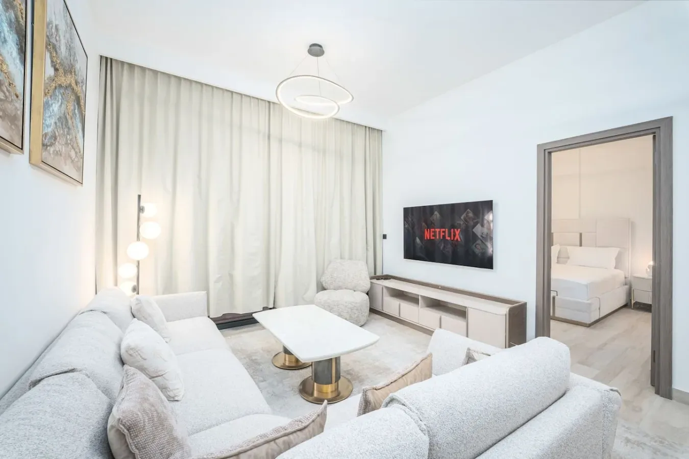 Una sala luminosa con asientos claros, una mesa de centro y un televisor.
