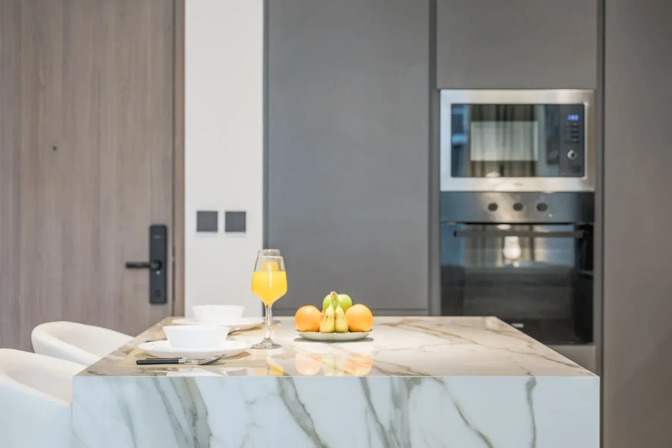 Una cocina moderna con una isla de mármol, fruta y electrodomésticos integrados.