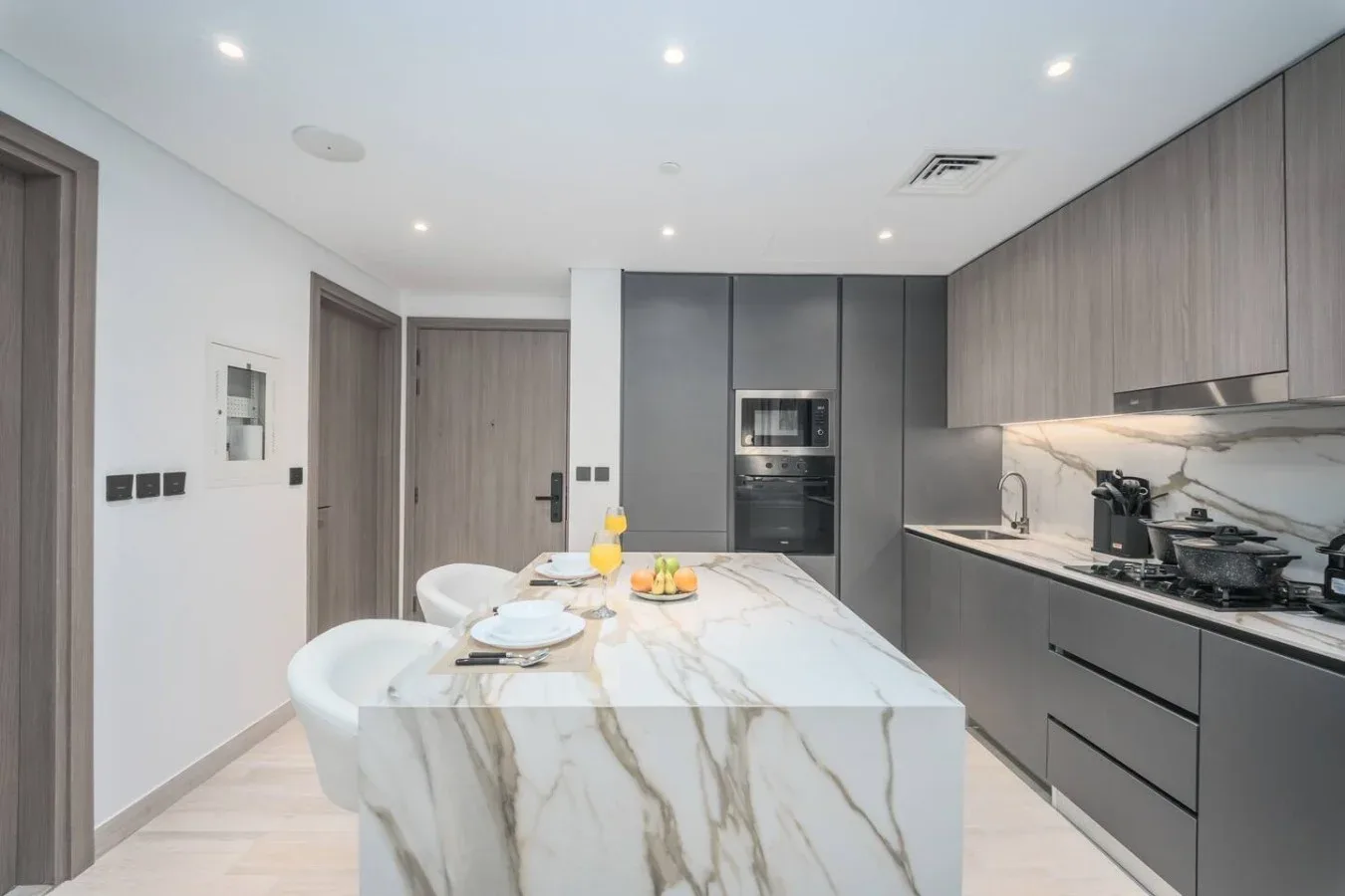 Una cocina moderna con una isla de mármol y gabinetes oscuros.
