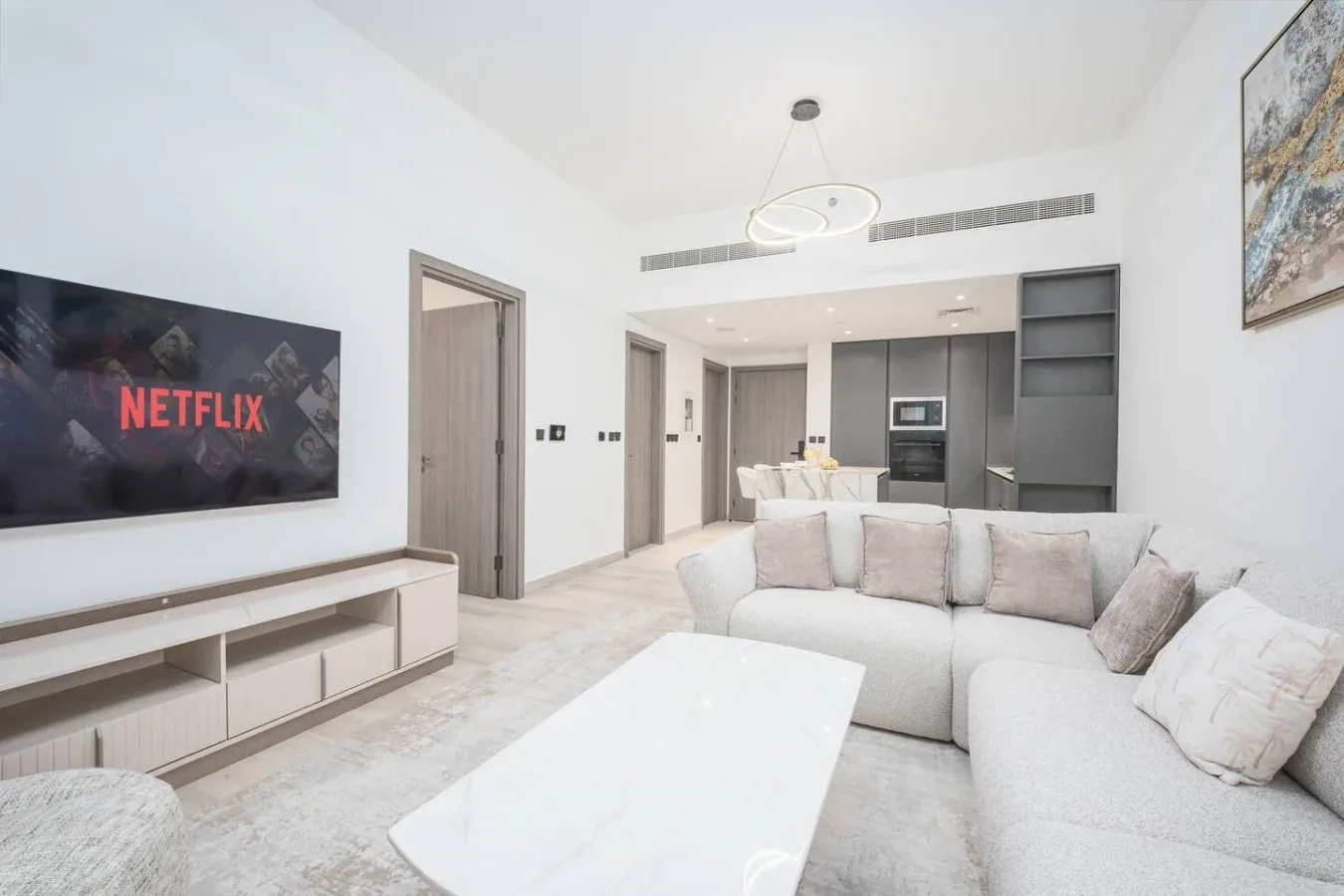 Una sala luminosa con un sofá seccional claro y una cocina abierta.