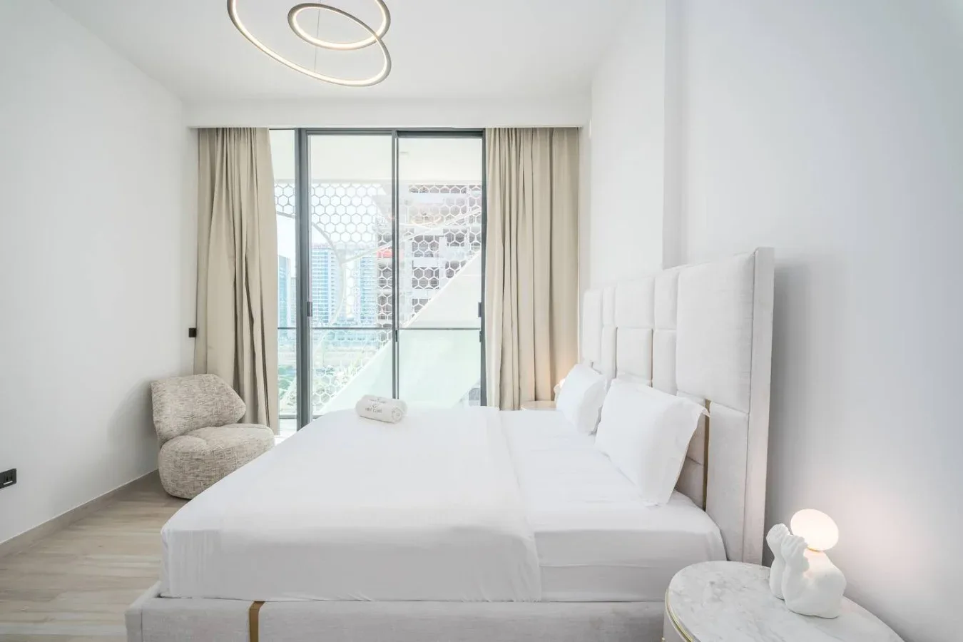 Un dormitorio luminoso con una cama grande junto a una ventana de suelo a techo.
