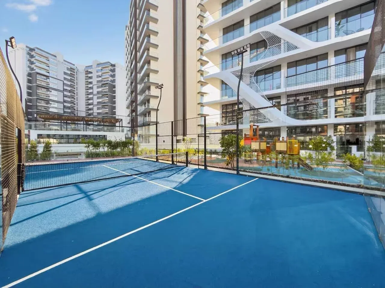 Una cancha deportiva azul al aire libre está rodeada de edificios modernos.