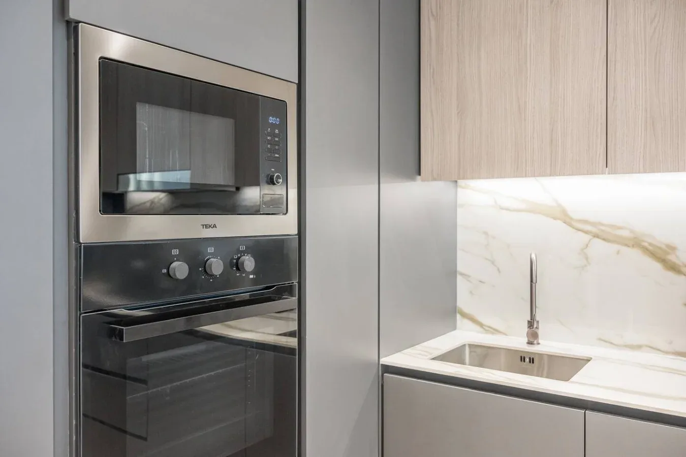 Una cocina moderna con horno empotrado, microondas y fregadero.