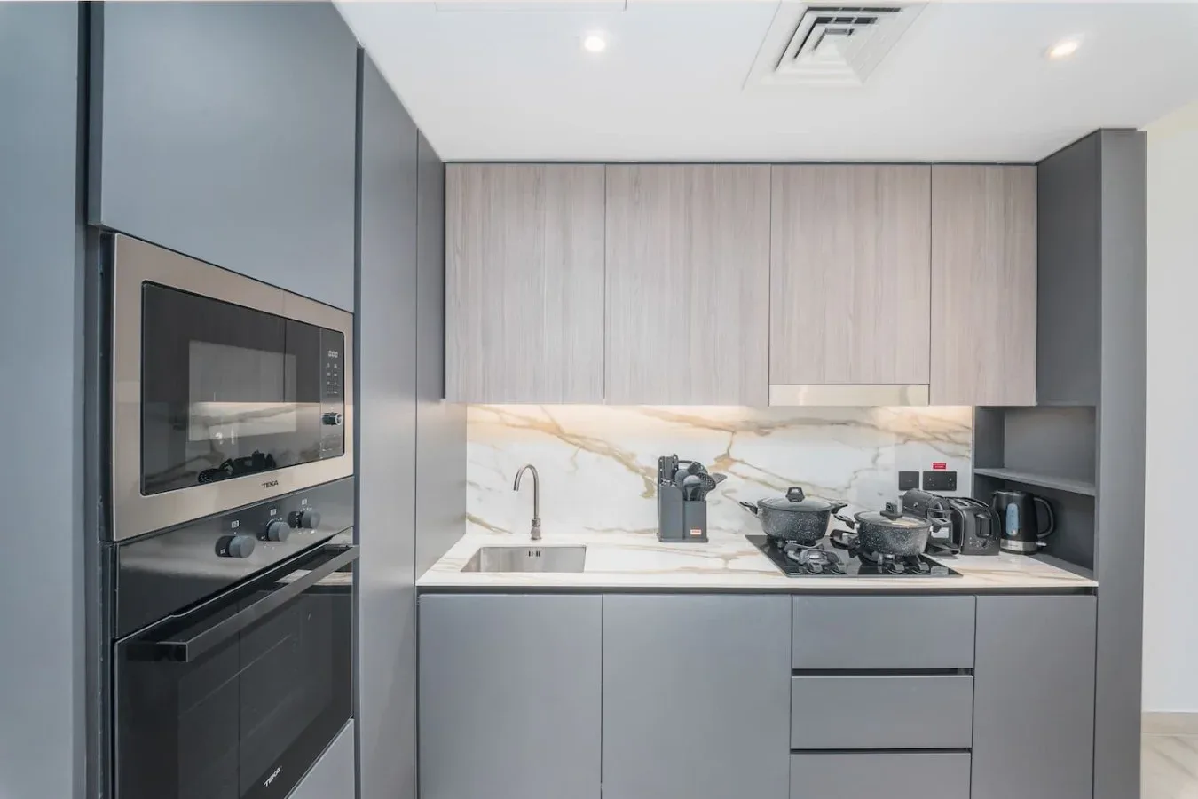 Una cocina moderna con electrodomésticos integrados y una zona de cocción sobre la encimera.