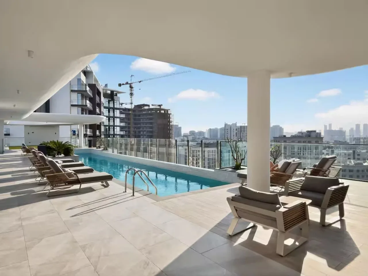 Una zona de piscina en la azotea con asientos para descansar da a edificios cercanos.