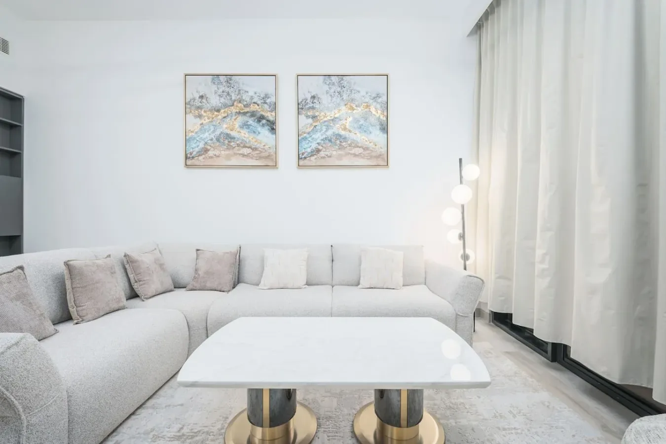 Una sala luminosa con un sofá seccional curvo y cuadros enmarcados.