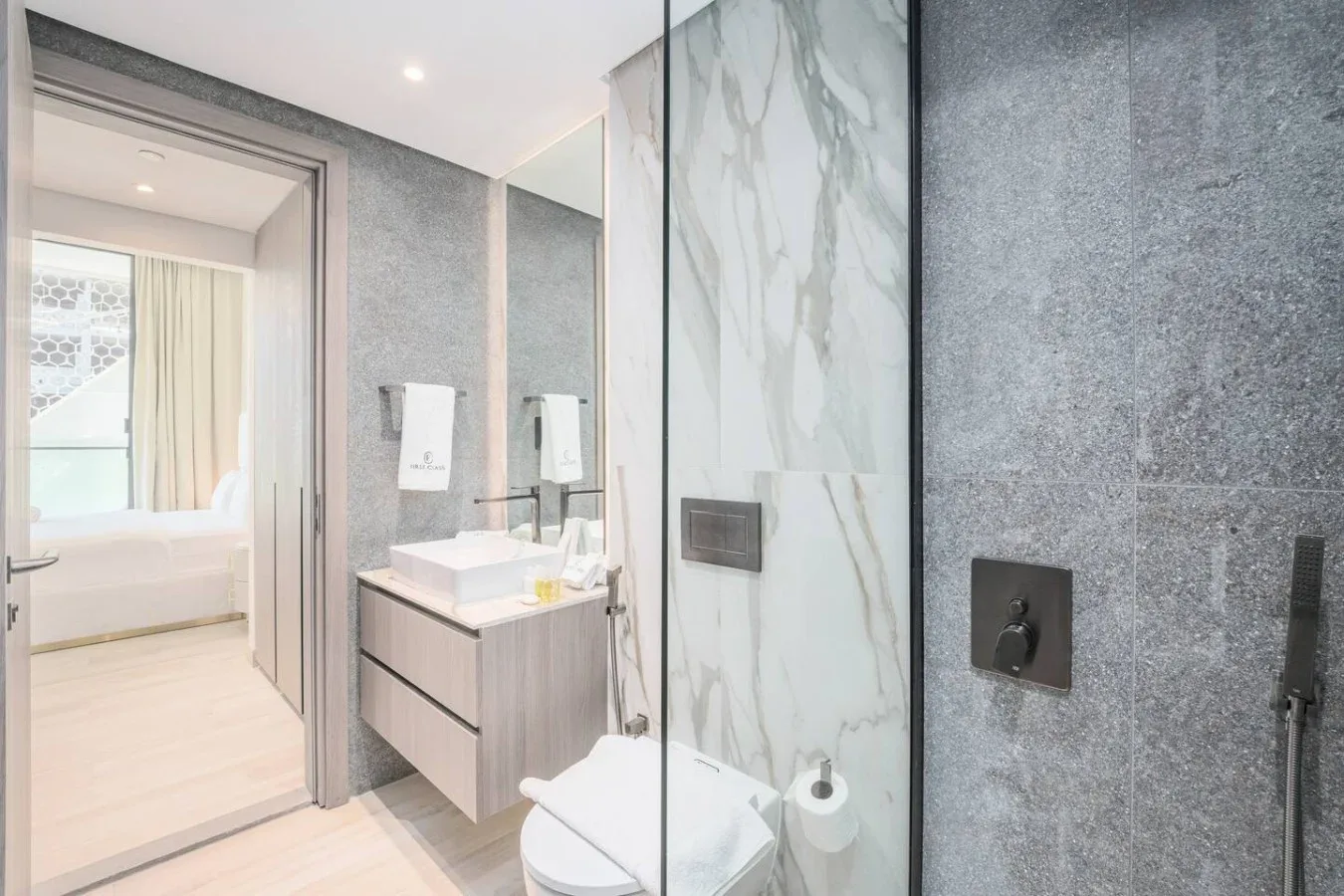 Un baño luminoso con tocador, inodoro y mampara de ducha de vidrio.