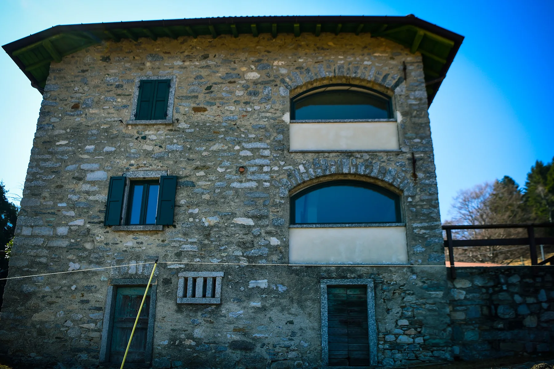 A stone house exterior with shuttered windows and a dark roof.