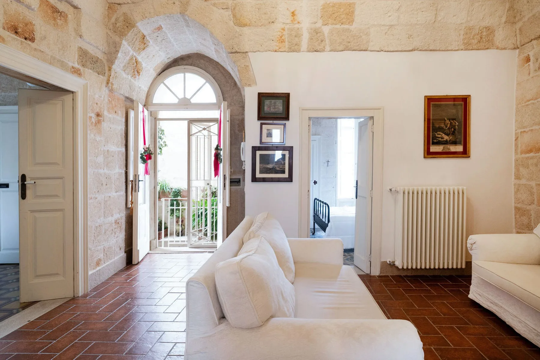 Una sala luminosa con asientos blancos y una puerta acristalada en arco.