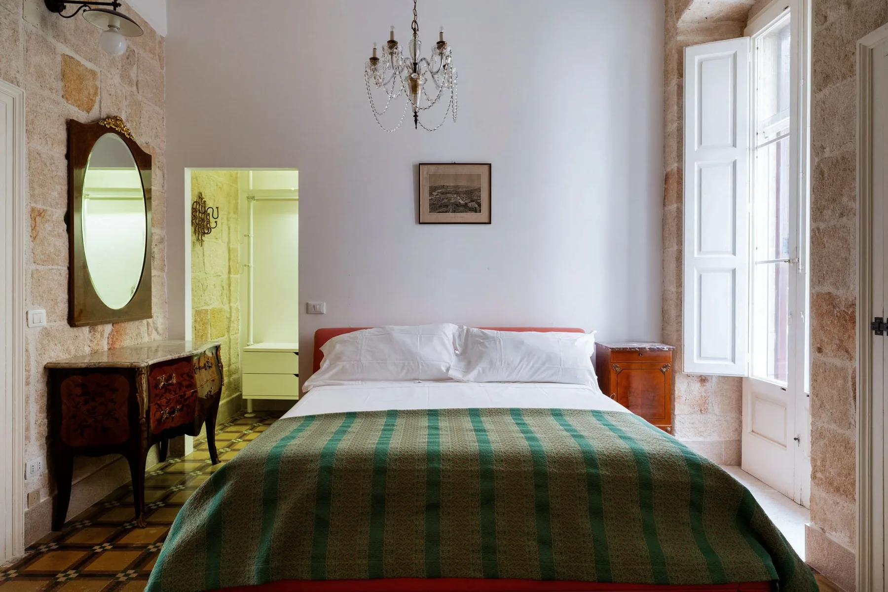 Un dormitorio con una cama cubierta por una colcha a rayas verdes y marrones.
