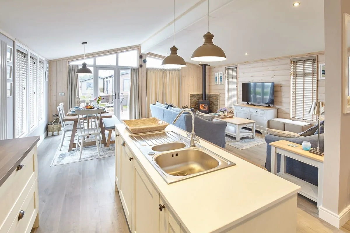 An open-plan kitchen and living area with a dining table by the windows.