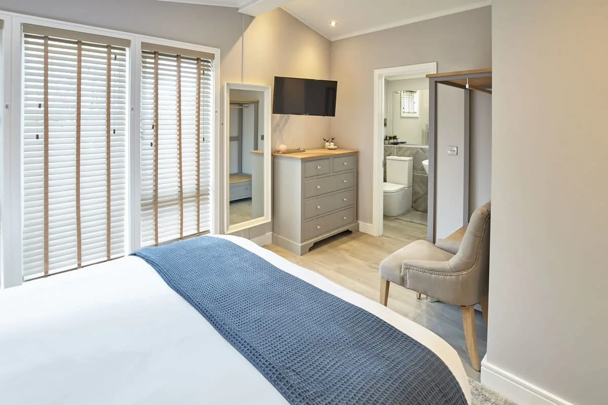 A bedroom with a neatly made bed, dresser, and television.