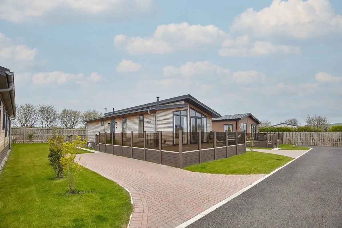 A modern single-story building with a fenced patio beside a paved path.