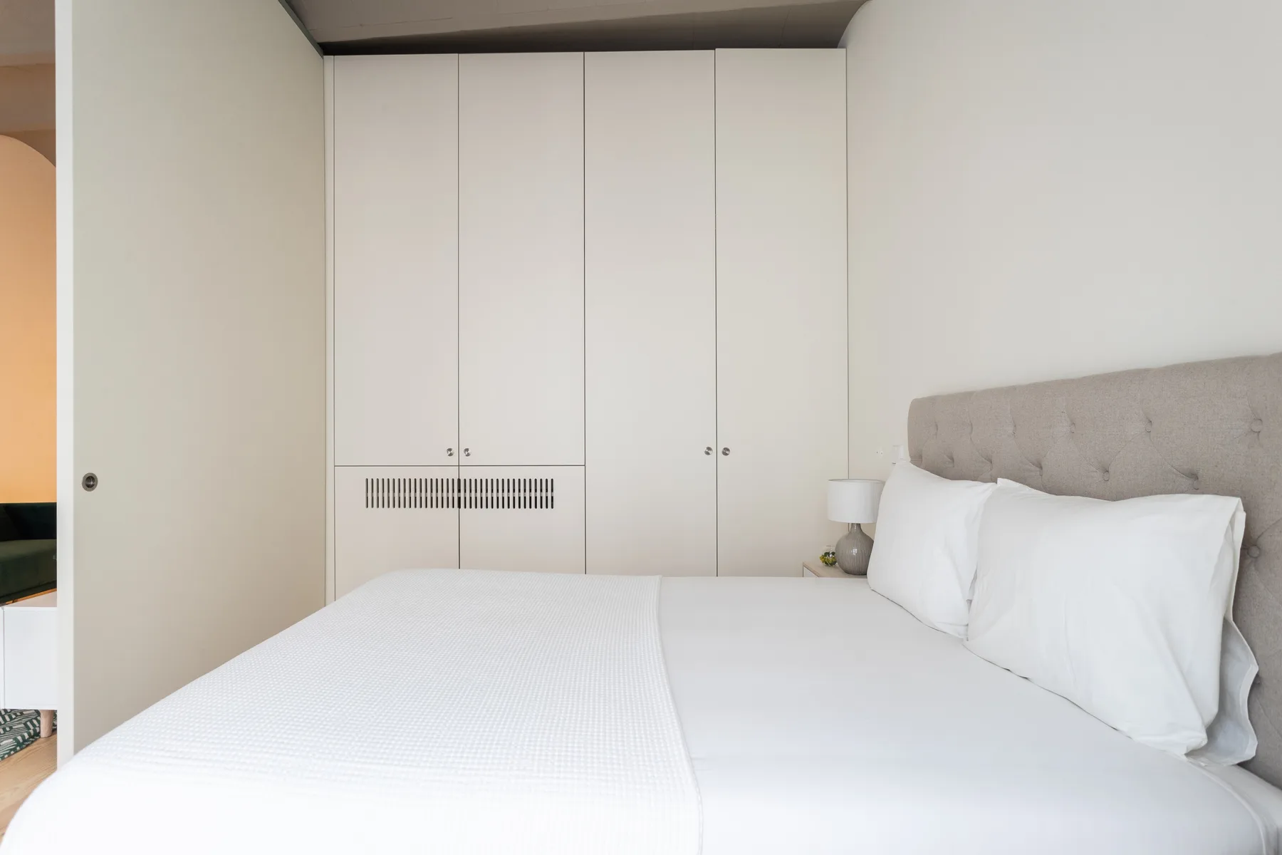 Un dormitorio luminoso con una cama bien hecha y armarios empotrados.