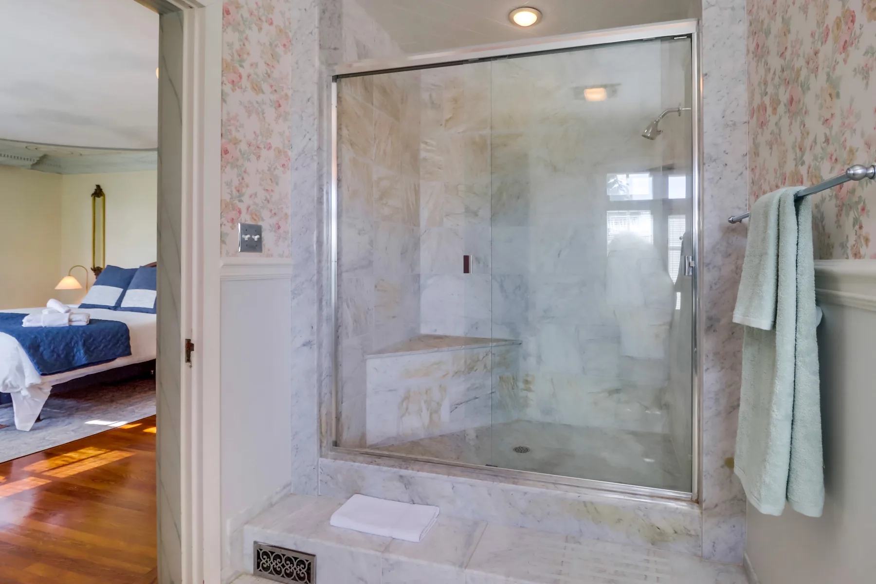 A bathroom shower with a built-in bench and towels hanging nearby.