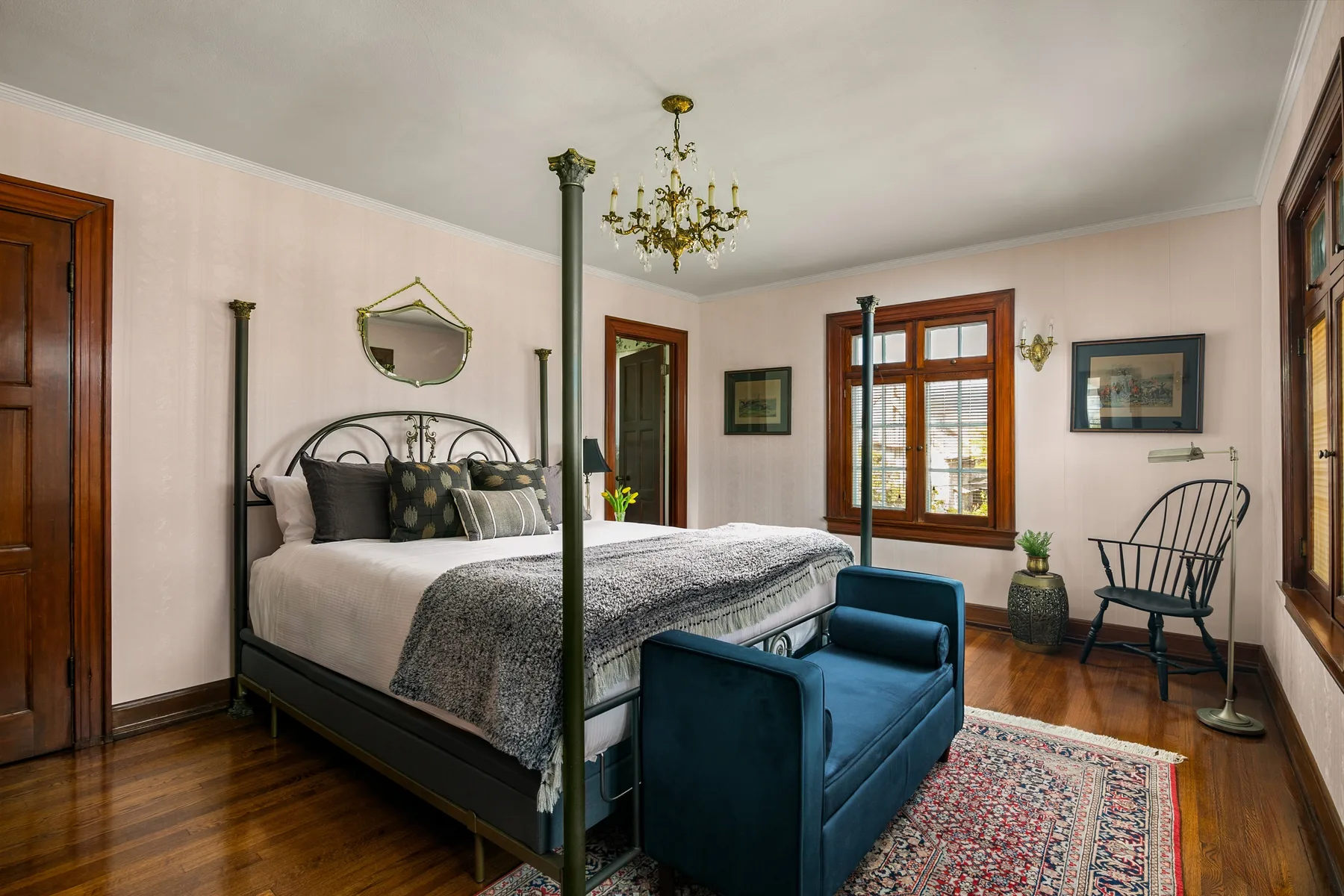 A bedroom with a metal bed, blue seating, and wood floors.