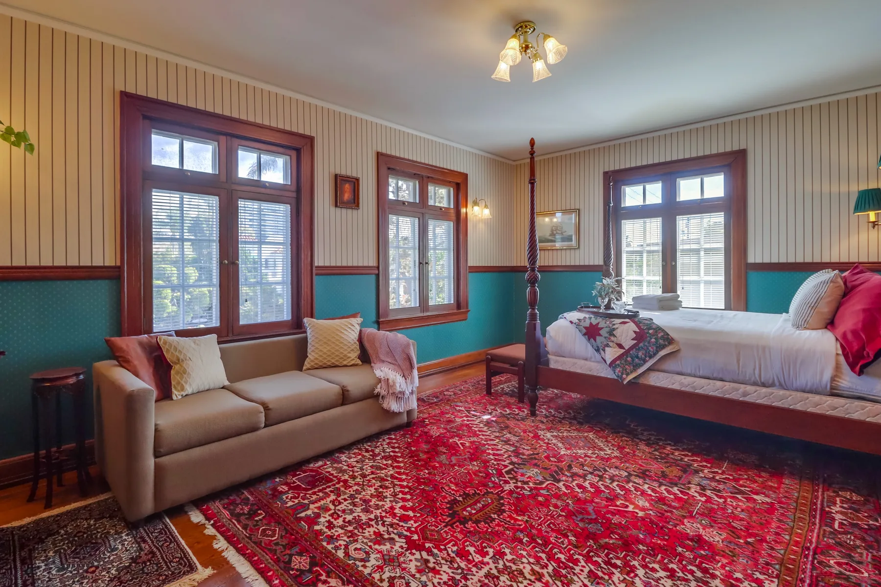 A bedroom with a bed, seating, and a patterned rug.