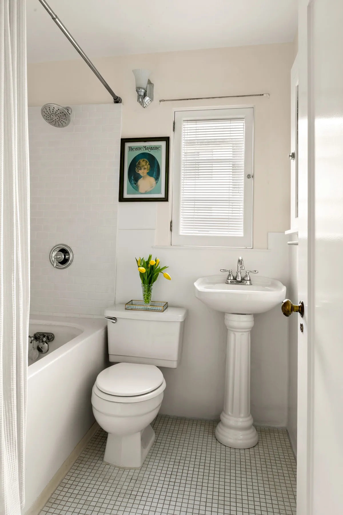 A bright bathroom with a bathtub, toilet, and pedestal sink.