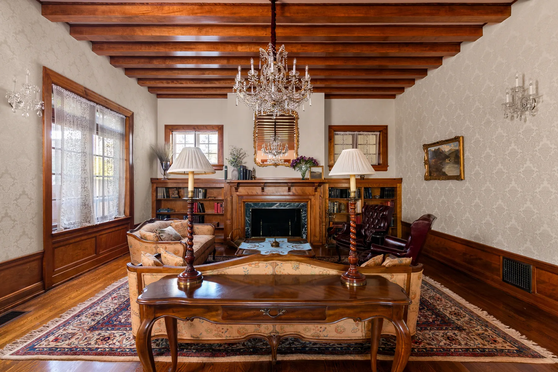 A traditional living room with wooden ceiling beams and a fireplace.