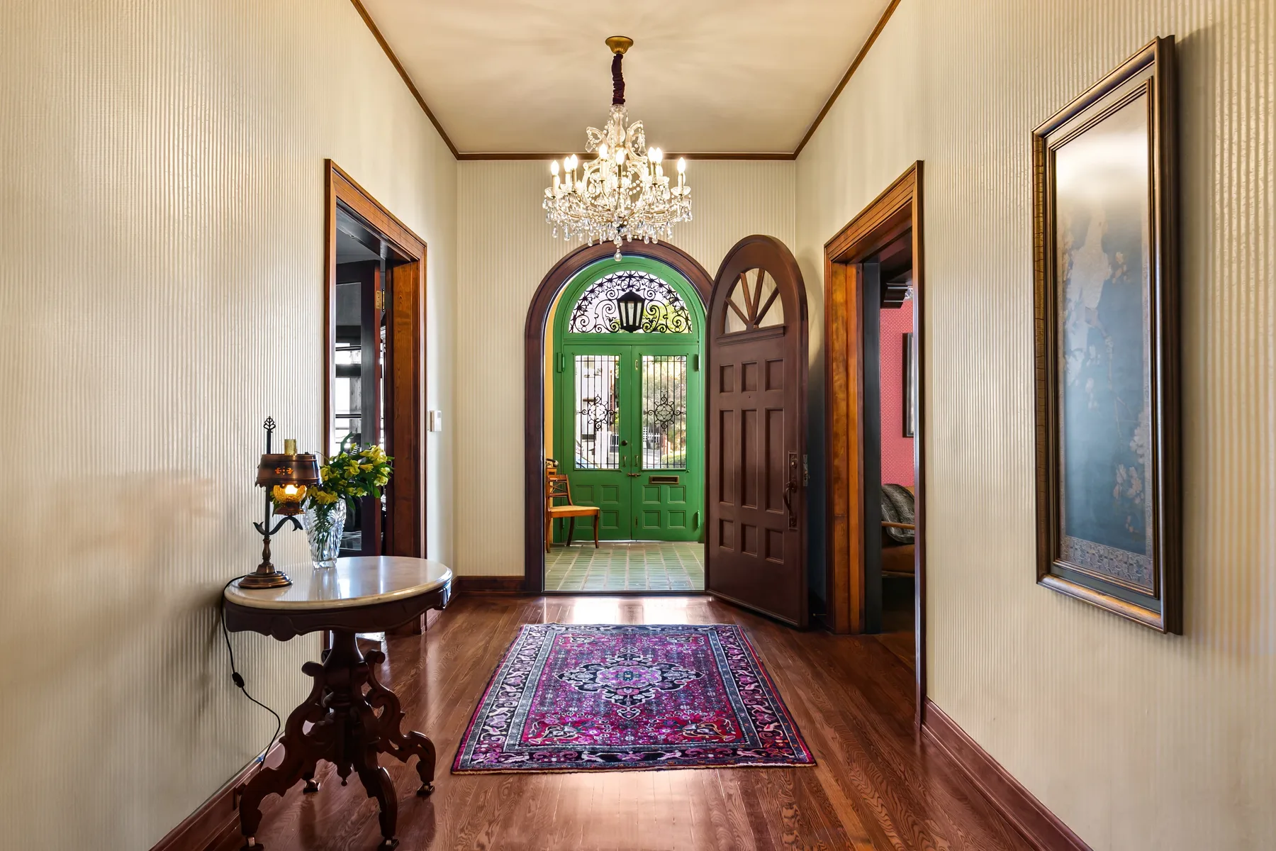 A narrow entry hall features a green front door and a patterned rug.