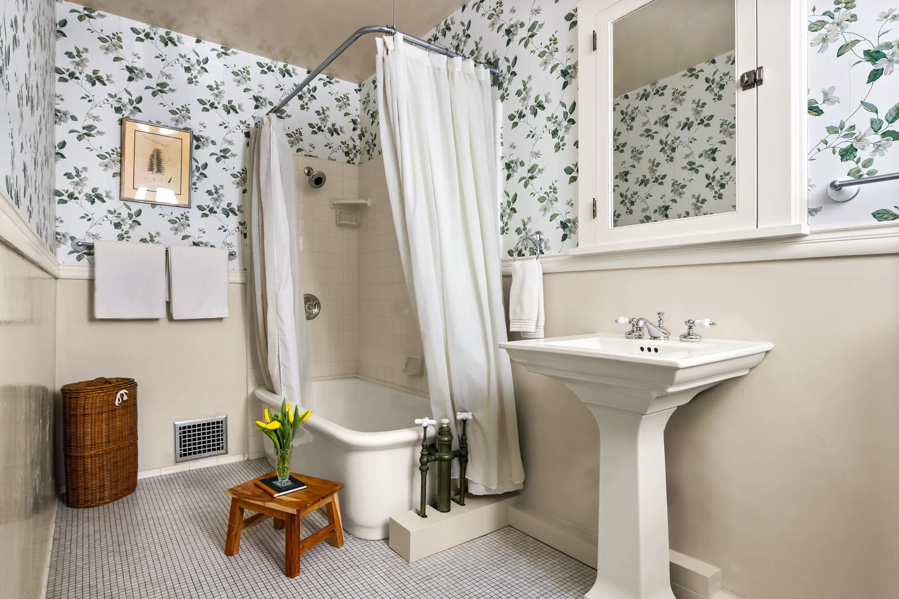 A bathroom with a curtained bathtub and a pedestal sink.