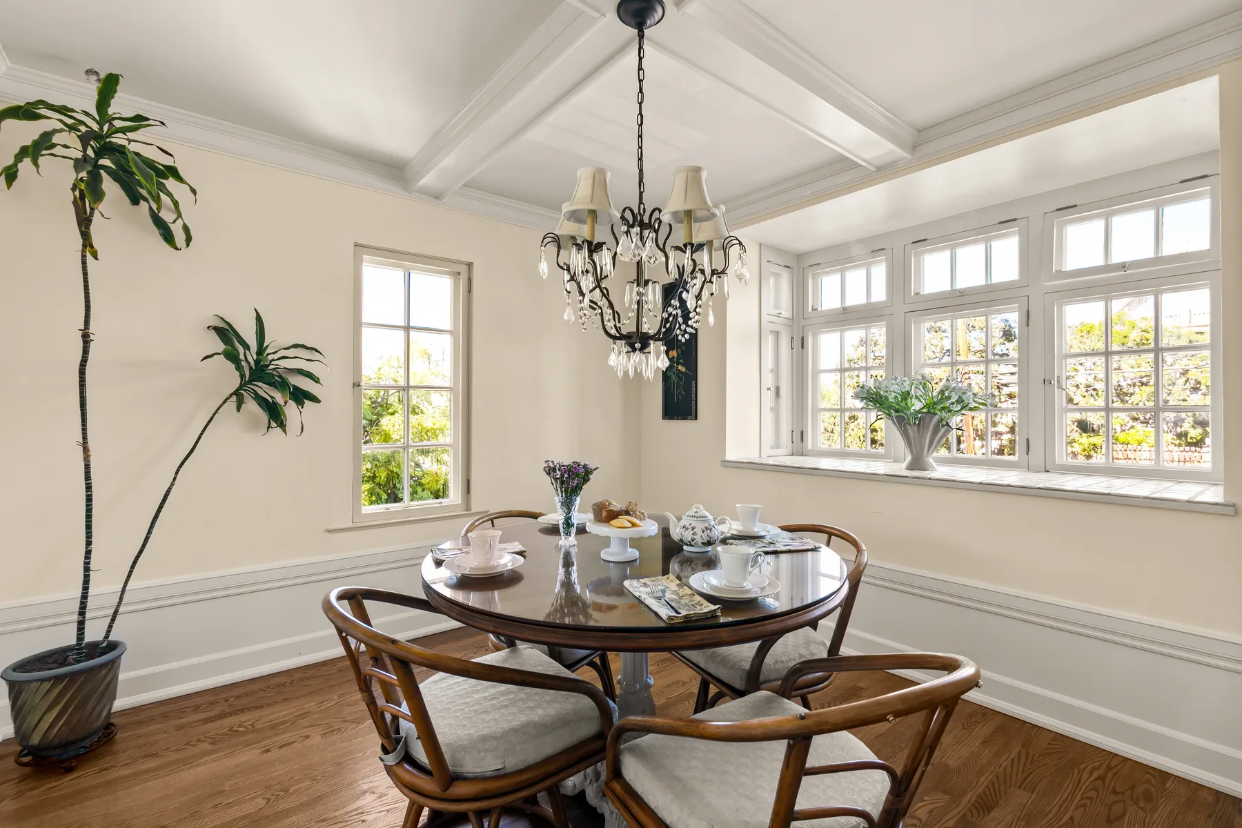A bright dining room with a round table beneath a chandelier.