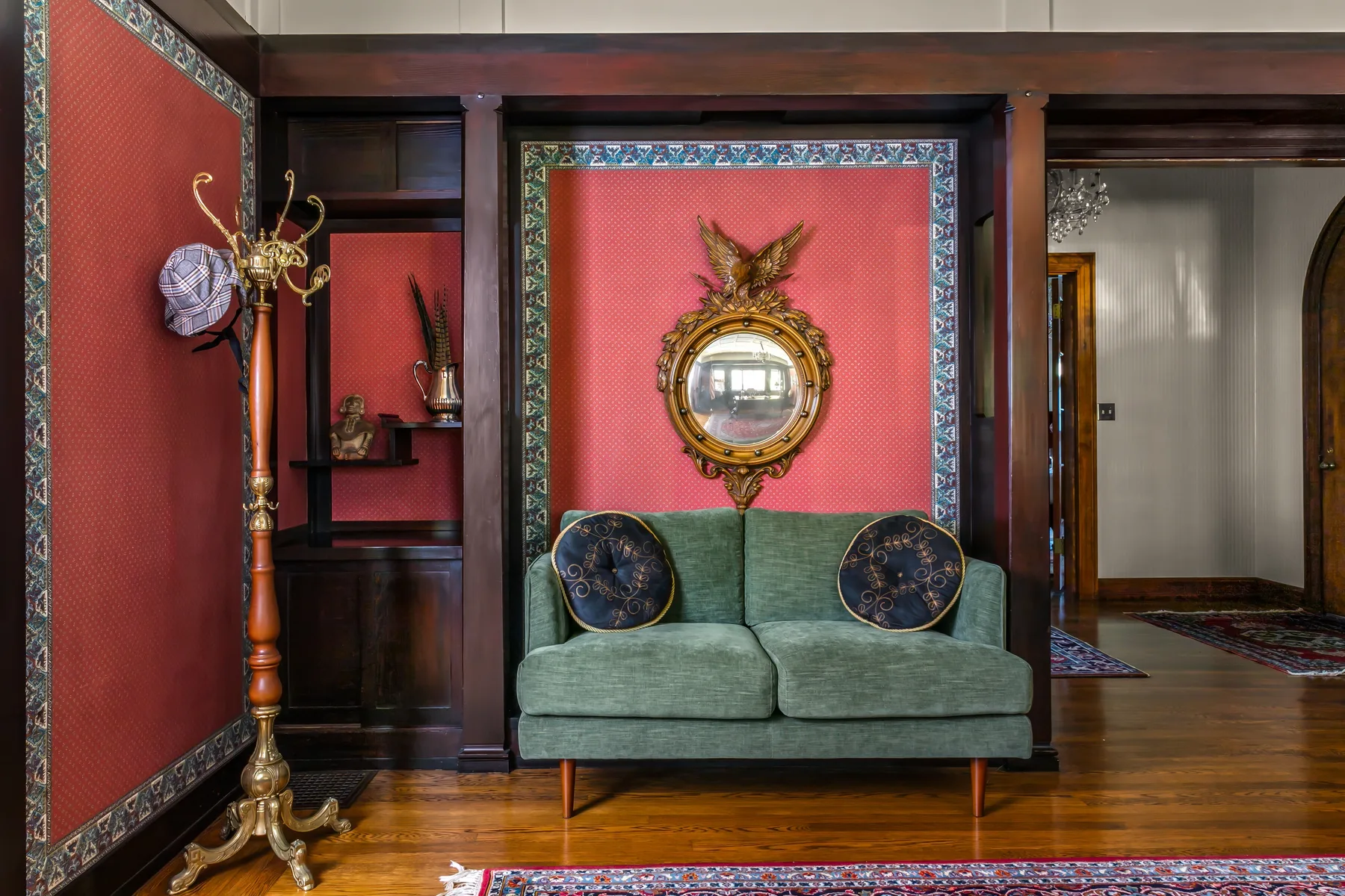 A sitting area features a green sofa against a red patterned wall.