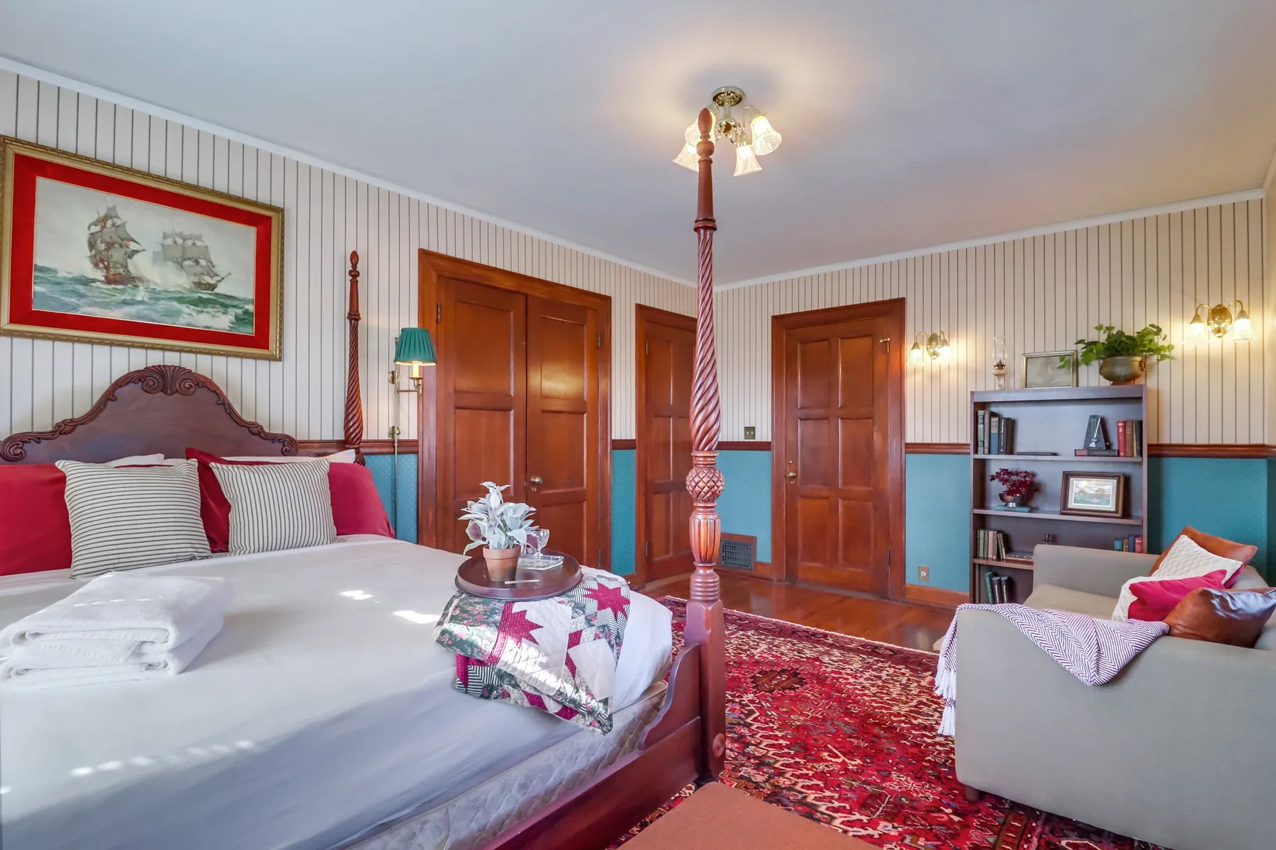 A bedroom with a large bed, patterned rug, and seating area.