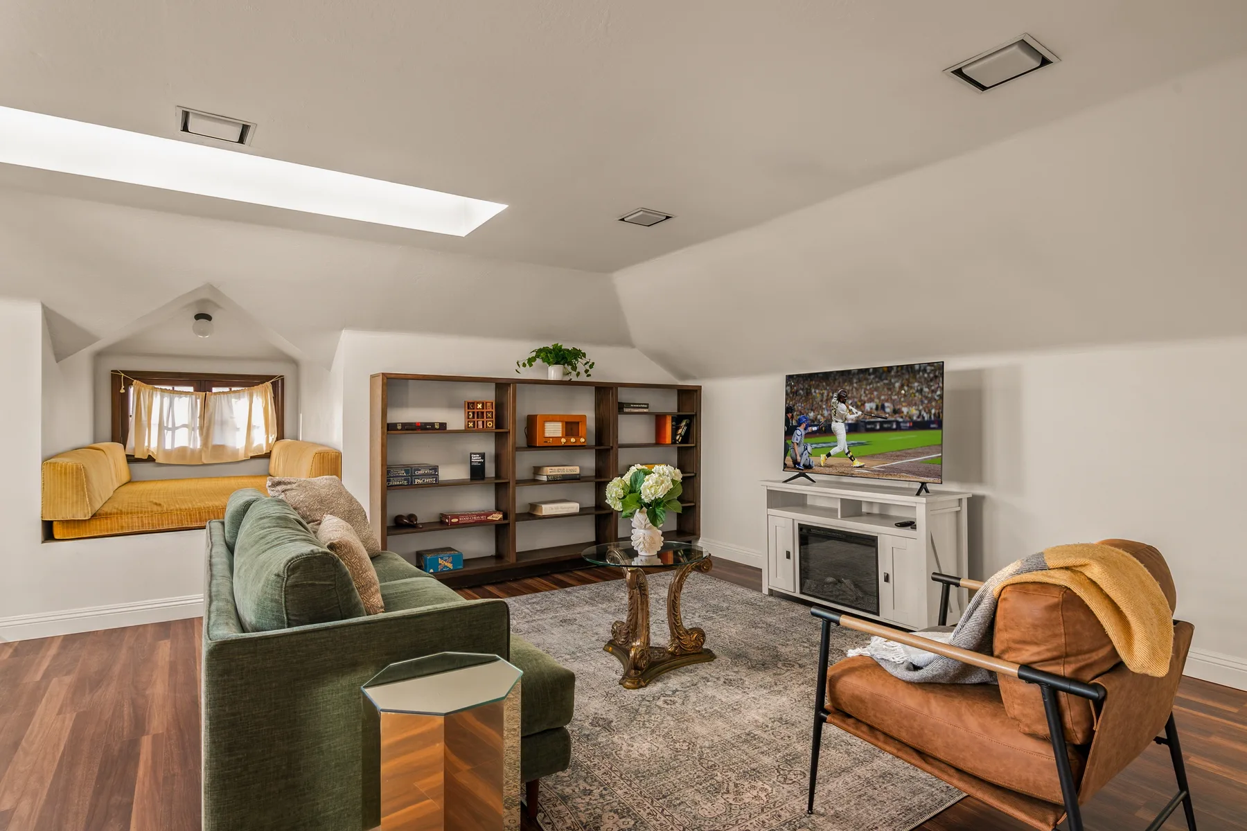 A bright living room with seating, bookshelves, and a television.