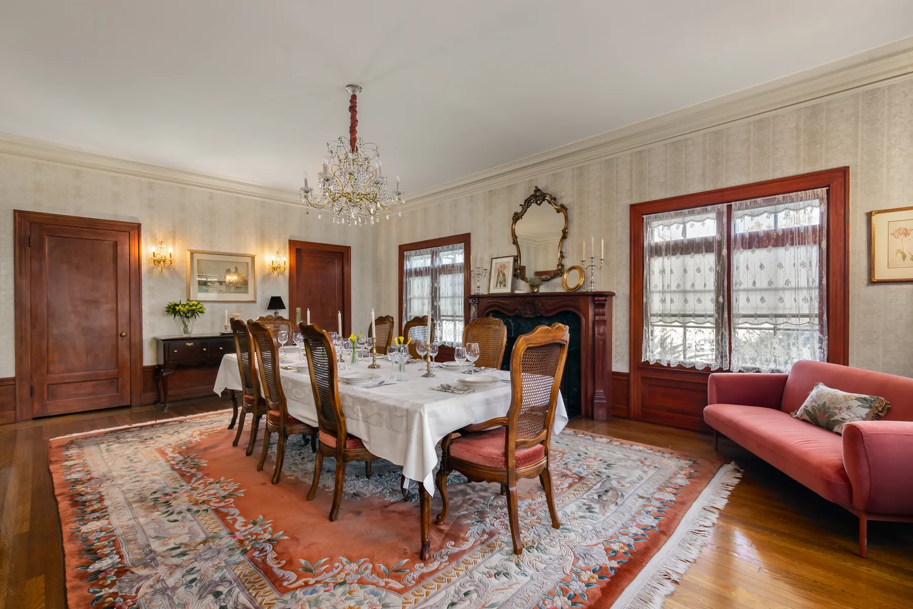 A formal dining room with a long table set beside a fireplace.